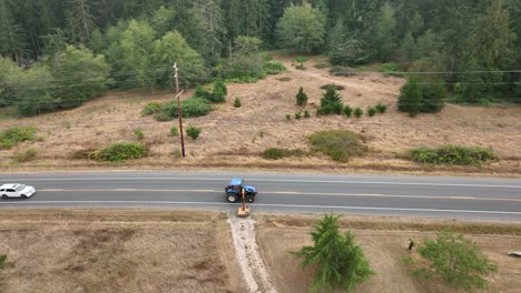 amplia toma aérea de un tractor con un accesorio de corte de pendiente y zanja cortando las malas hierbas