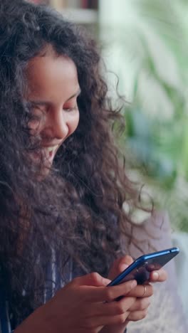 young indian woman teenager makes victorious wave of hand an holds phone