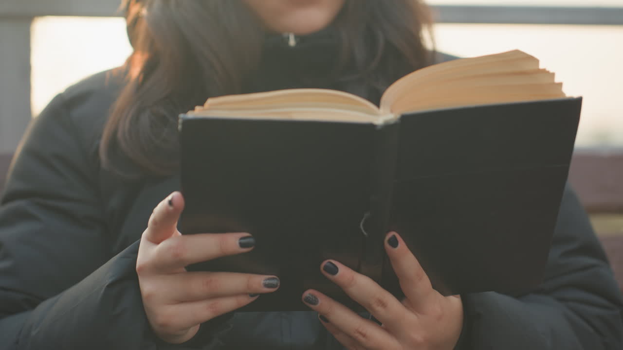 Primo piano di donna in un ambiente esterno. Donna contemplativa che legge su un tranquillo tetto al tramonto. Donna introspettiva che legge un libro all'aperto con la calda luce del tramonto e un ambiente sereno.