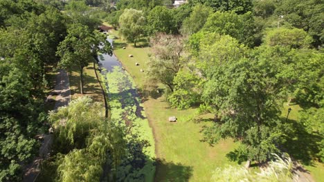 Una-Vista-Aérea-De-Un-Dron-Sobre-Un-Parque-En-El-Arroyo-Del-Valle,-Nueva-York,-Con-Un-Arroyo-Reflectante-Y-Un-Estanque