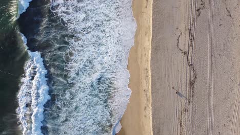 Menschen-Gehen-Mit-Ihren-Hunden-Am-Strand-Spazieren,-Während-Die-Wellen-Am-Sandstrand-Brechen