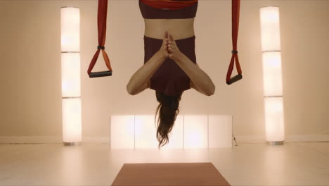 sportswoman doing handstand on yoga mat. woman hanging upside down in hammock