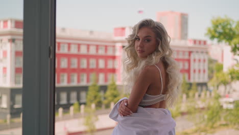 woman in lacy bra and sagged white bathrobe on terrace