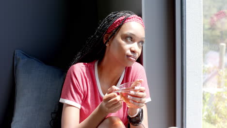 african american young woman holding smartphone, looking outside