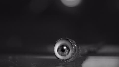 eyeball, covered in blood, on a table, with the pupil looking around, in a horror film style vfx low angle close up shot