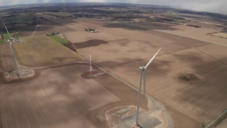 Vista-Aérea,-Dos-Turbinas-Eólicas-En-Medio-De-Un-Campo-De-Agricultores