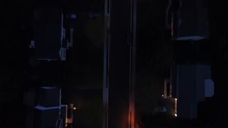 aerial top down shot of lighting lantern on main street of dark neighborhood at night, usa. parking cars in front of single family homes. birds eye shot. pennsylvania, united states of america.