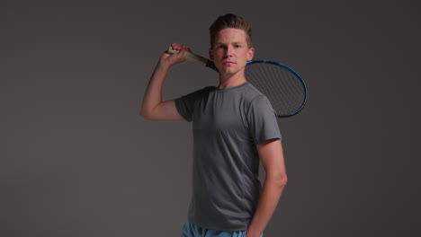 Studio-Portrait-Of-Male-Tennis-Player-Holding-Racket-Shot-Against-Grey-Background-1