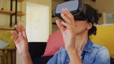 mujer caucásica sonriente con auriculares vr, sentada en el suelo en casa