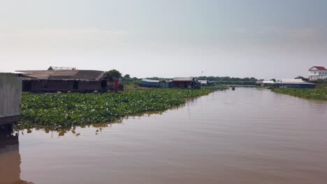 travelling down the river near tonle sap in cambodia past floating houses and boats