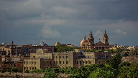 shot of an old church surrounded by city buildings in valletta, the capital of malta on a sunny day