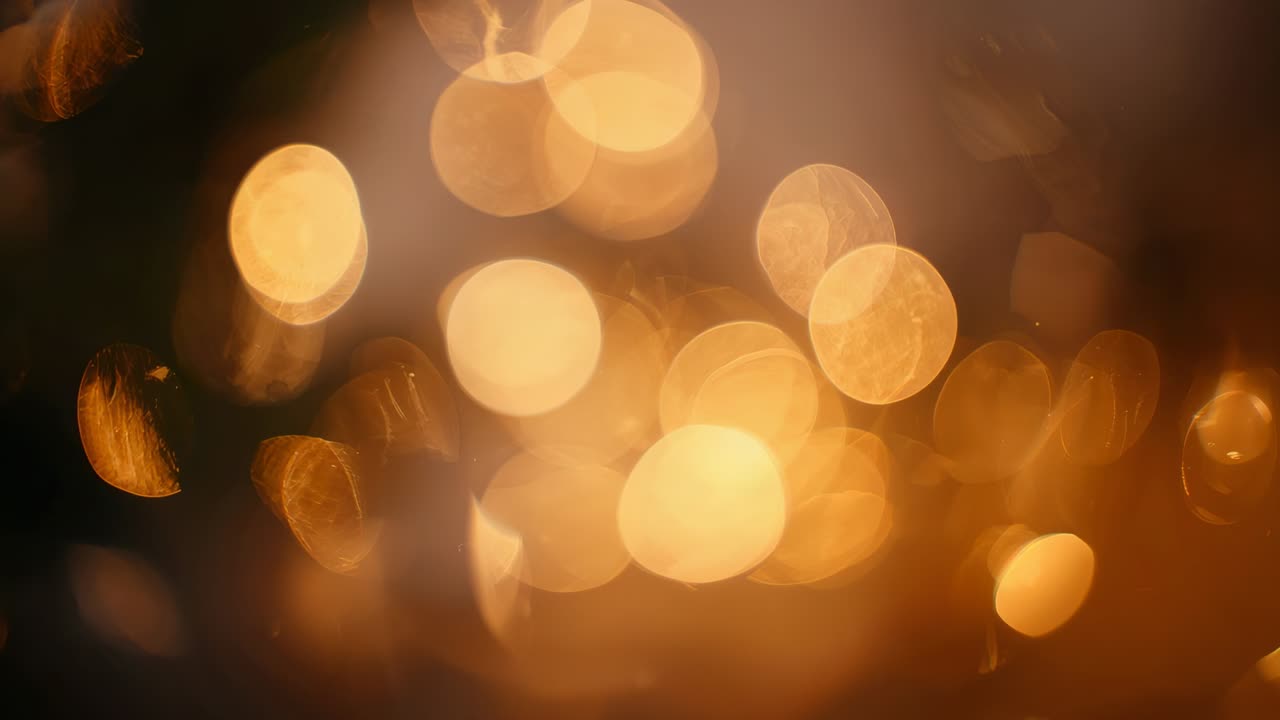Shimmering warm bokeh lights shifting from soft focus in dim room, showing hex facets, leaf shadow