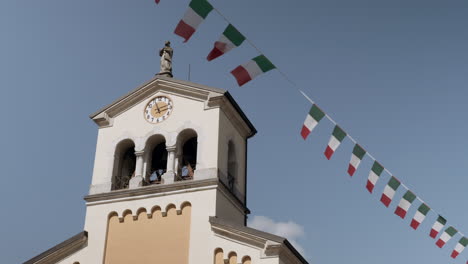 italian church tower with clock and flag