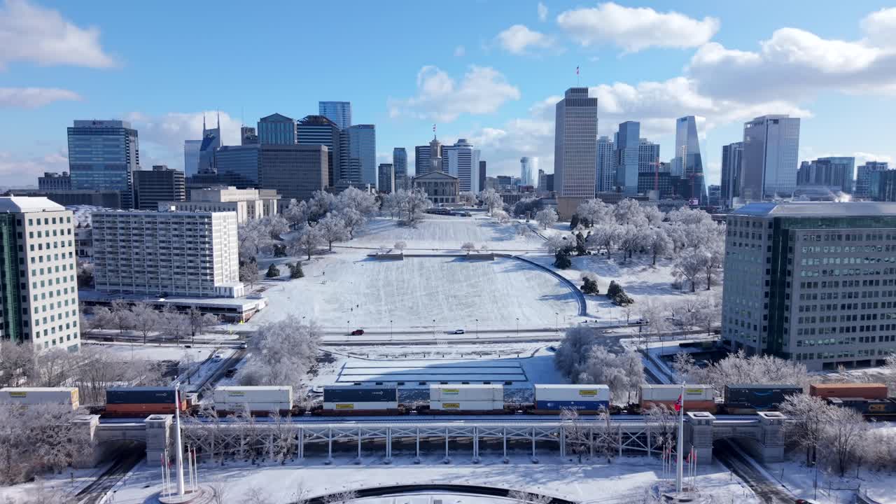 Skyline ghiacciato di Nashville, che mostra il Campidoglio dello Stato del Tennessee coperto di neve e il paesaggio urbano che luccica alla luce del sole invernale - approccio aereo frontale mattutino