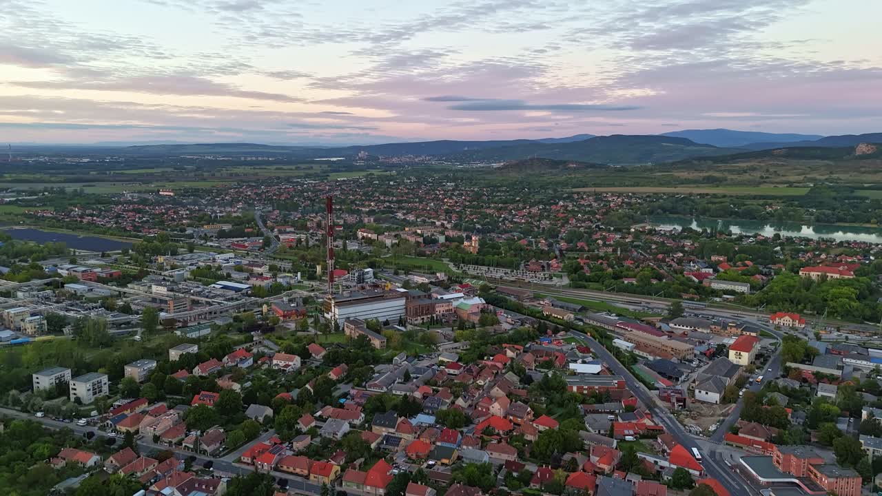 Aerial hyperlapse towards Dorog downtown, showing the vibrant industrial city during a cloudy sunset in Hungary