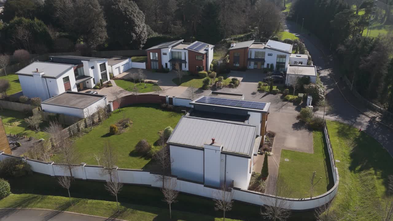 Aerial view of curved road around varied modern houses with flat roofs, minimalist yards and woodland backdrop conveying tranquil luxury eco estate