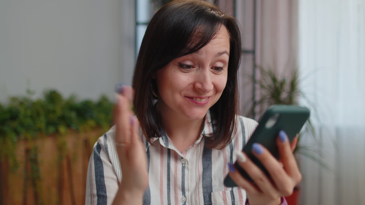 Donna freelancer felice e vincitrice che usa lo smartphone, celebra la vittoria per buone notizie, esclamando "Wow, sì!".