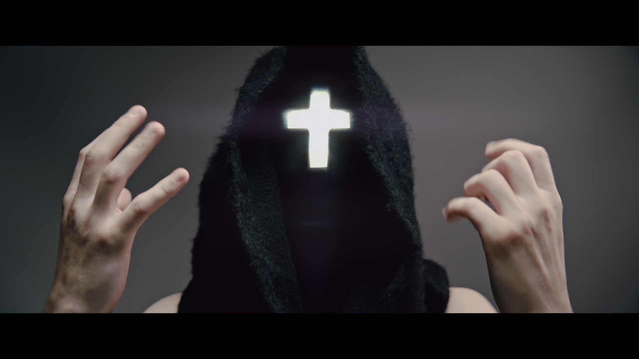 Masked man with cross of light glowing on his face prays