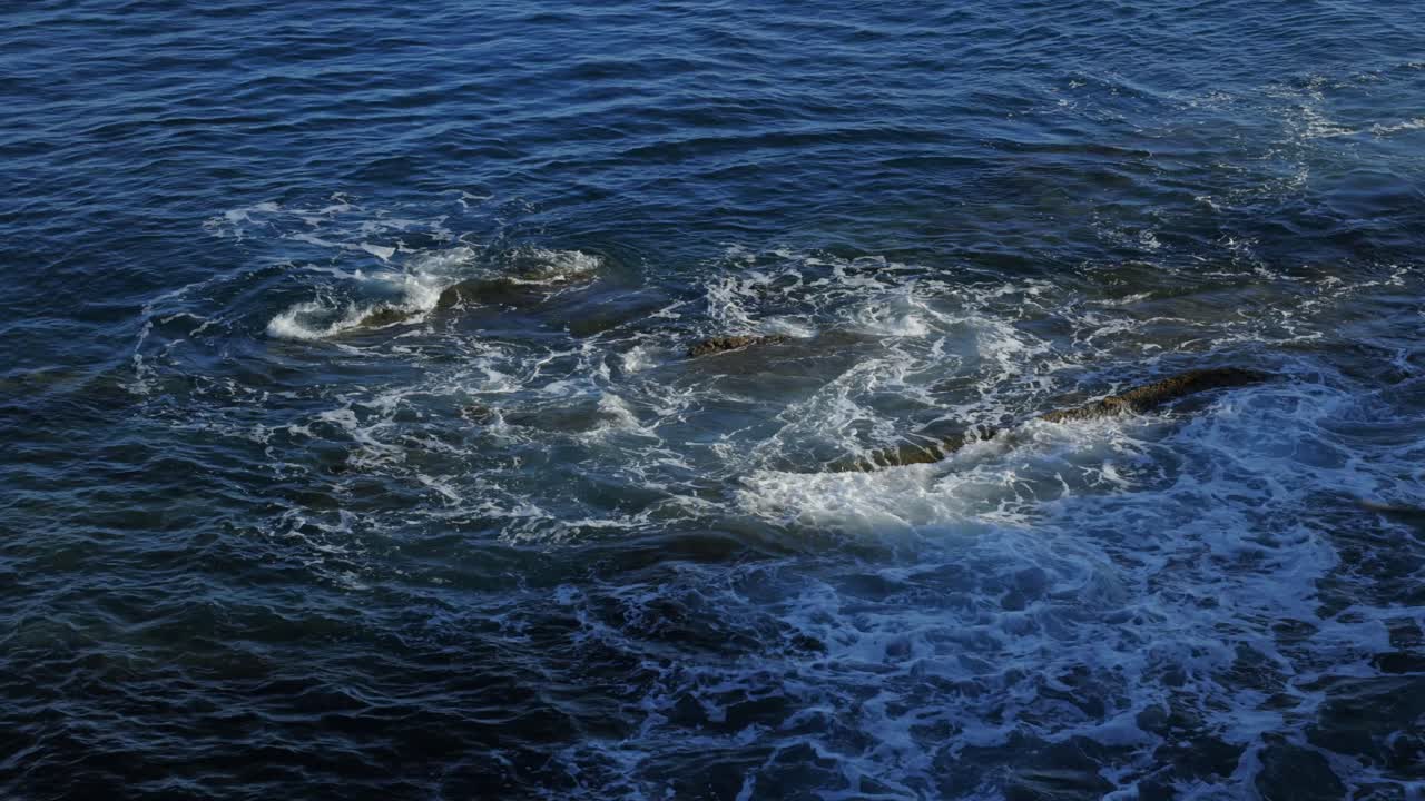 Opspattende zeegolven op rotsen, kustlijn Italië