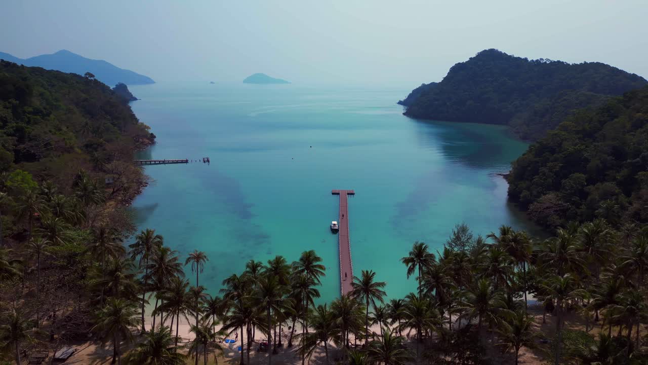Scenic aerial view of lush green hills and turquoise waters on Koh Chang Ngam Island. Smooth aerial view flight fly reverse drone