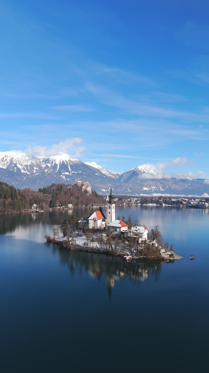 Vista aerea verticale con drone del lago di Bled con la chiesa sull'isola dell'Assunzione di Maria Vergine e il castello in inverno, Alpi Giulie, Bled, Slovenia