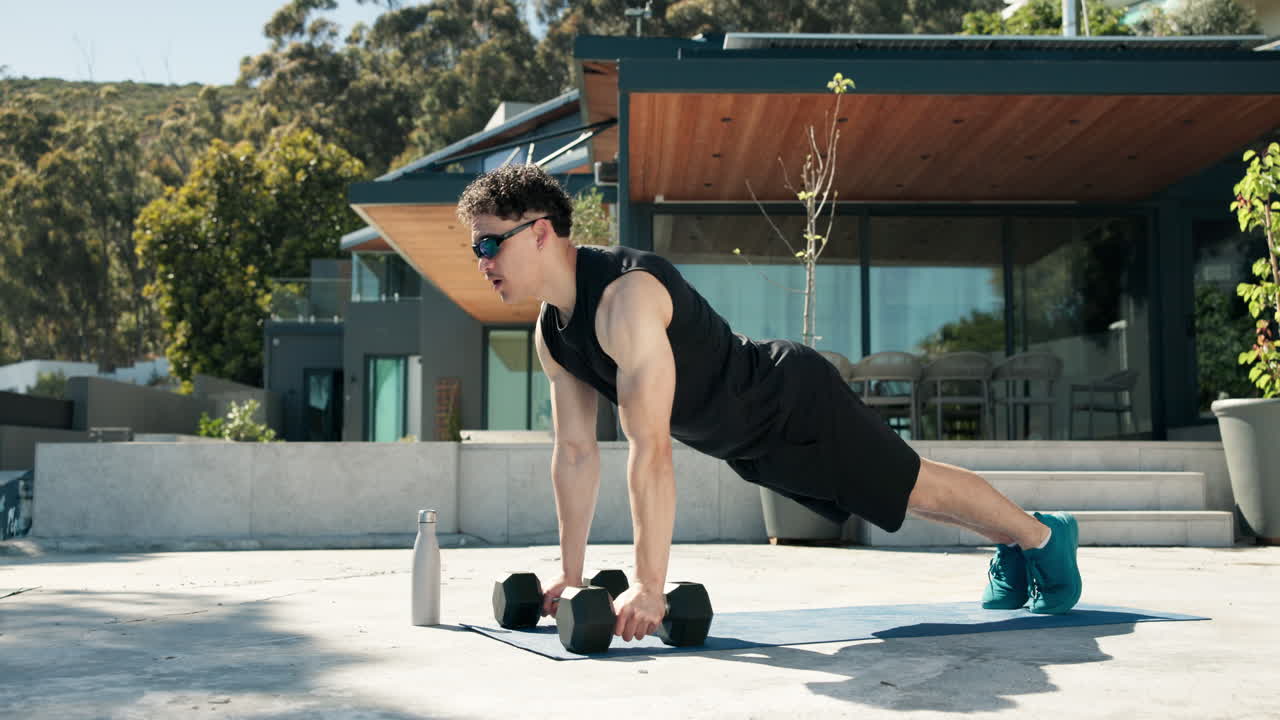 Man Doing Push-Ups with Dumbbells on Outdoor Patio