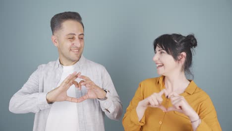 couple making heart sign at camera.