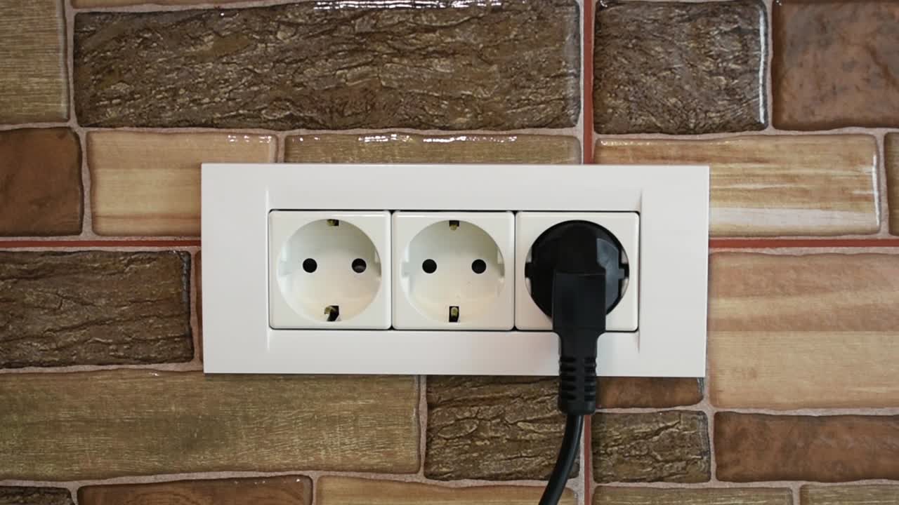 Woman's hand connecting a device in a triple power wall socket, third position