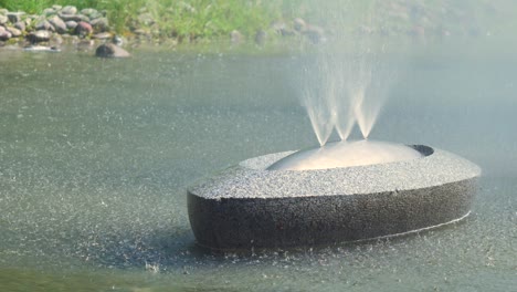 view on water splashing from isolated fountain “sun boats” in jaunpilsētas square in ventspils in sunny summer day, medium closeup shot