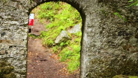 arco de piedra que conduce a un sendero forestal