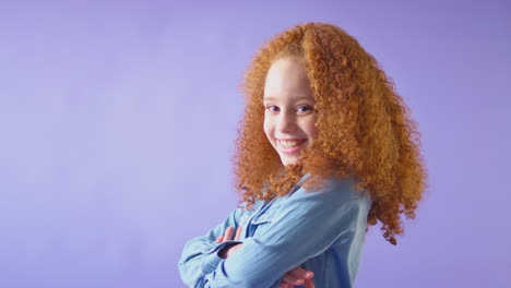 studio portrait of smiling girl with red hair against purple background