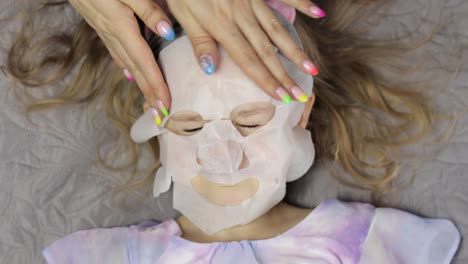 teen girls mother applying moisturizing face mask on daughter. child with cosmetic facial skin mask