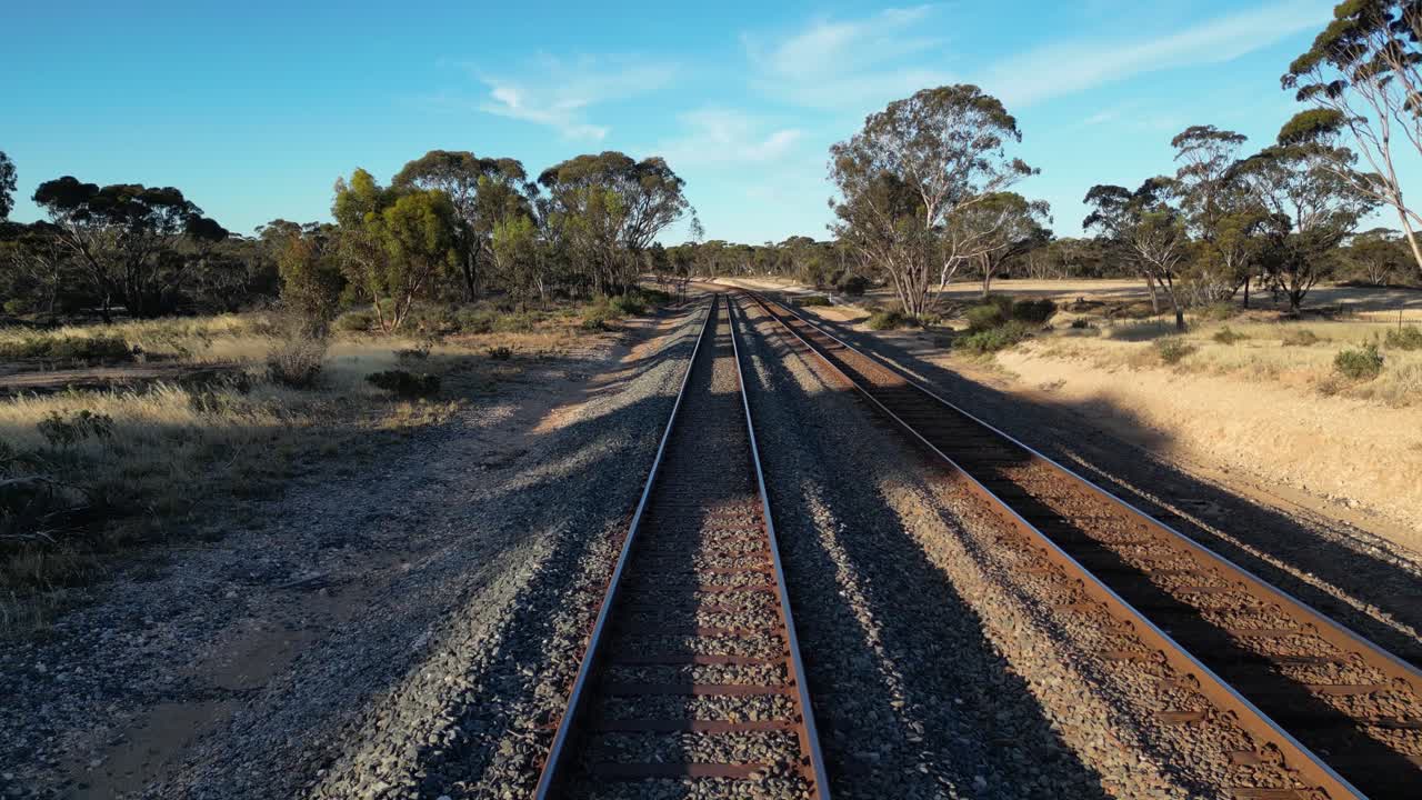해가 지는 동안 오스트레일리아의 모래 숲 지형에서 기차 레일 위의 공중 비행