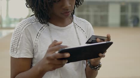 Focused-African-American-woman-typing-card-number-on-tablet.