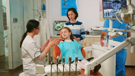 stomatologist explaining to little girl the cleaning process of teeth
