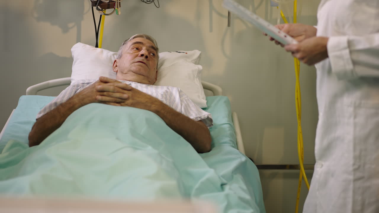 An elderly patient in a hospital bed being attended by a doctor