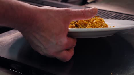 un camarero sirve un plato de paella valenciana