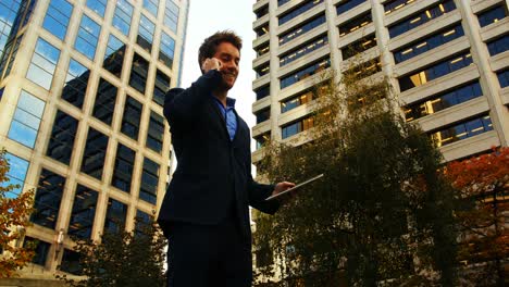 Businessman-talking-on-mobile-phone-and-holding-digital-tablet