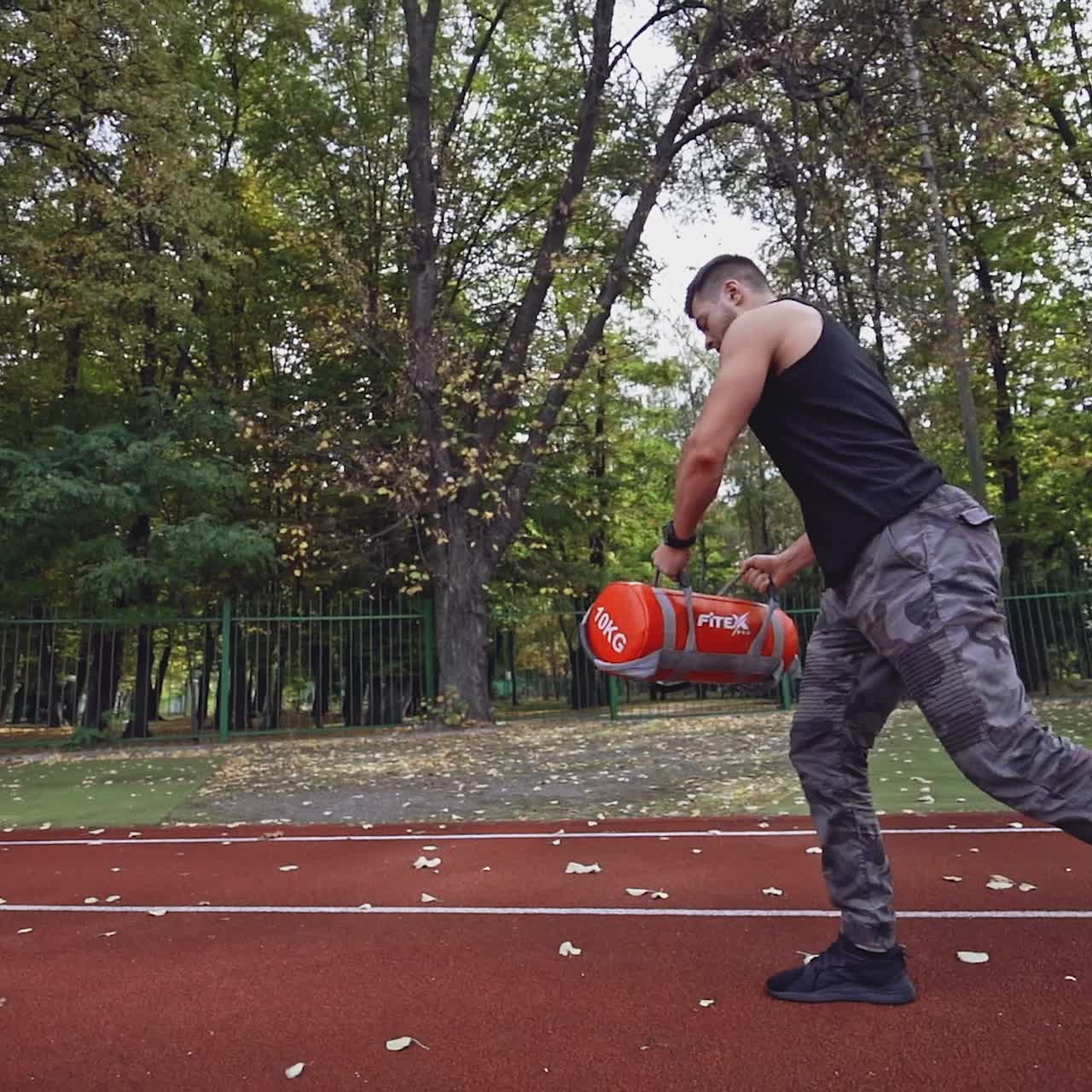 Fitness man exercises outdoors in autumn. Healthy sportsman training his muscular body with weight in the modern stadium.