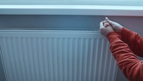 manos encendiendo la temporada de calefacción de cerca, la mujer haciendo la temperatura de la batería más tratando de mantenerse caliente en invierno