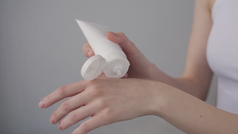 detail of a woman's hands applying cream to the back of her hands