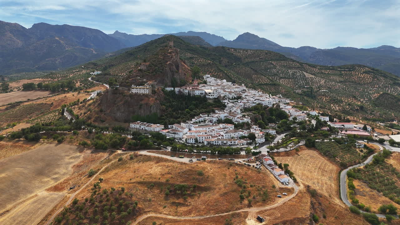 Aerial drone footage of Zahara de la Sierra village and castle surrounded by mountains in Andalusia, southern Spain