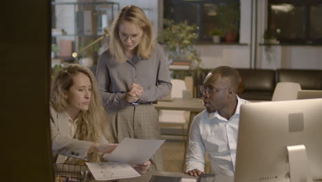 businesswoman analyzing printed business report and talking with her team in the office