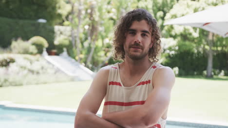 young caucasian man with curly hair smiles, arms crossed in a relaxed pose