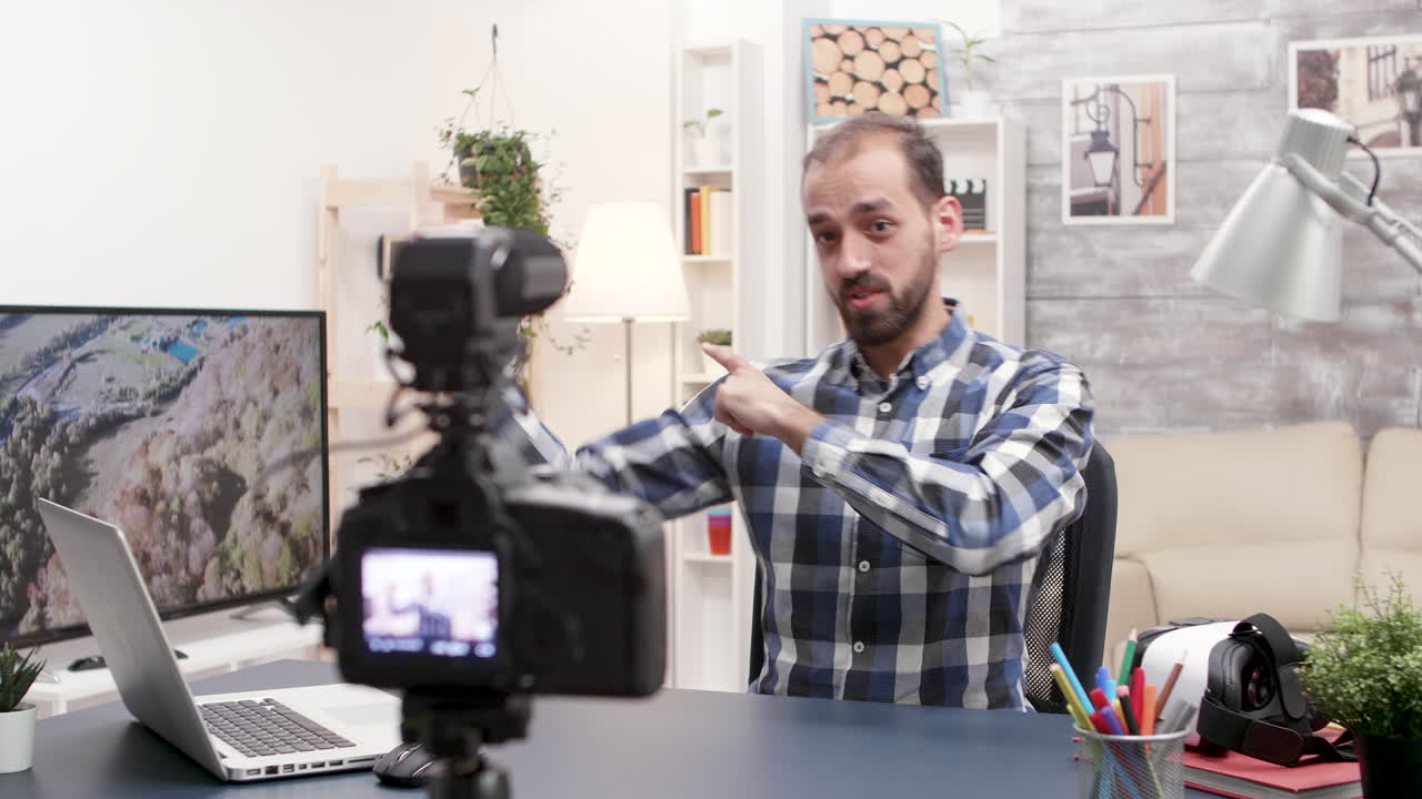Man recording vlog with camera and laptop in studio