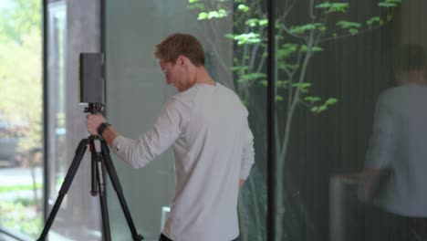 profesional tomando medidas para un plano 3d de una casa moderna usando un dispositivo matterport