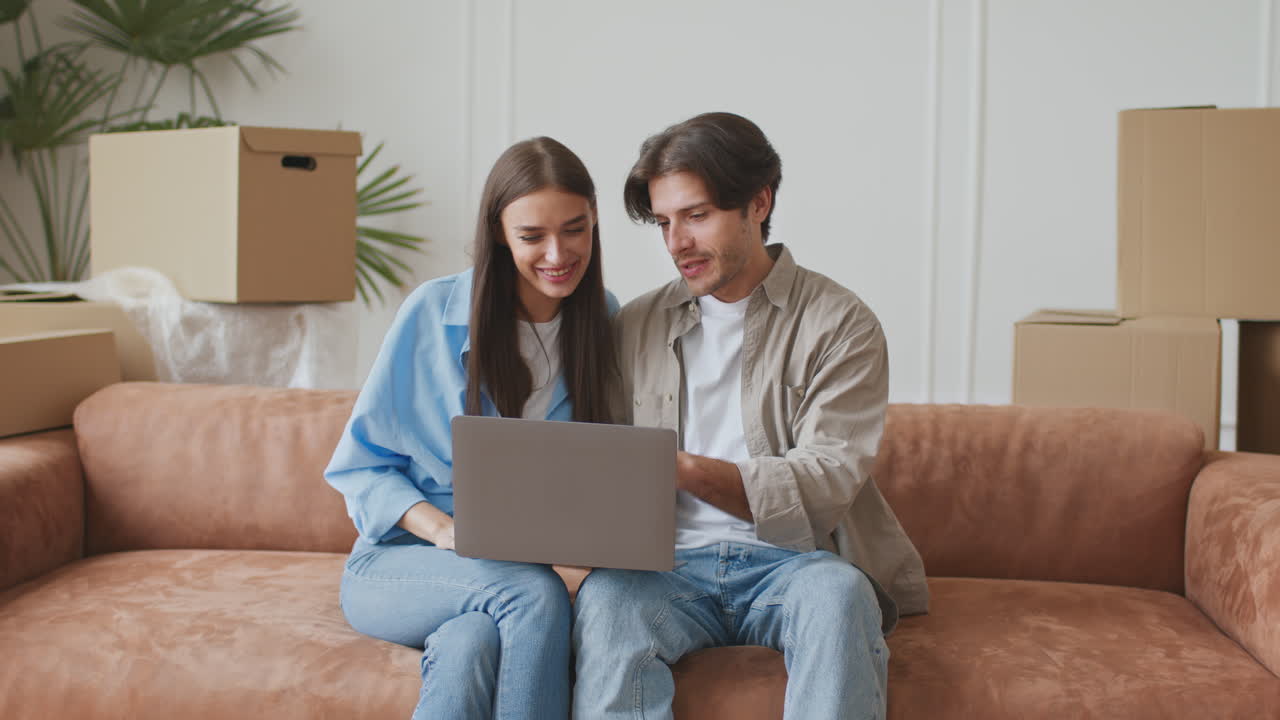 pareja que se mudan juntos y usan la computadora portátil para la organización