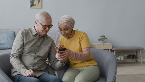 Arabic-Woman-Teaching-An-Elderly-Man-To-Use-A-Smartphone-1