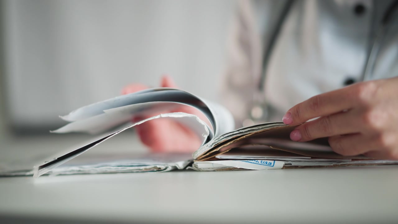 Registration handling in busy office. Detailed view of healthcare worker sorting forms swiftly at desk. Caring professional methodically managing patient forms during busy administrative day