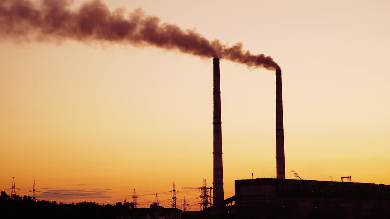 Fumo da ciminiera industriale. Silhouette della centrale elettrica al tramonto